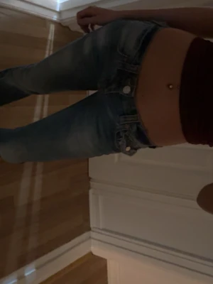 Blå bootcut jeans från True Religion - Säljer ett par blå bootcut jeans från True Religion med klassiska kontrastsömmar och broderad ficka bak. Jeansen har låg midja, fem fickor och är i mjuk denim med snygg tvätt. Perfekta för dig som gillar en avslappnad men trendig look.