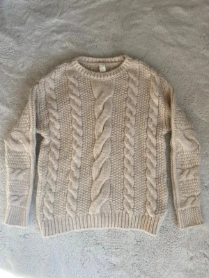 Beige kabelstickad tröja - Mysig beige kabelstickad tröja från H&M med grovt mönster och rund hals. Köpt second hand så jag vet ej hur många gången sen har använts men den är i bra kick! 