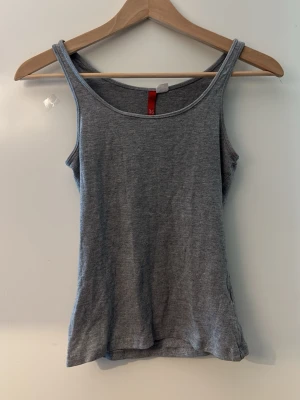 Grå enkel linnetopp - Snygg grå linnetopp med smala axelband och rundad halsringning. Perfekt basplagg i mjukt bomullsmaterial, lätt att matcha till olika outfits. Enkel och stilren design utan mönster eller detaljer.