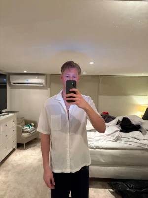 Vit kortarmad skjorta urban outfitters - Säljer en vit skjorta med korta ärmar och klassisk krage. Skjortan har en bröstficka och knäppning framtill. Materialet ser ut att vara lätt och luftigt, perfekt för varma dagar. Passformen är normal och skjortan har en enkel, stilren design.