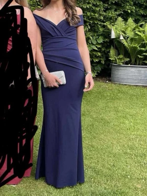Marinblå balklänning - Elegant marinblå långklänning från Bubbleroom med  v-ringad omlottdesign. Det går att ha den både offshoulder som jag har på bilden, och med armarna uppe! Klänningen har figurnära passform och går nästan hela vägen ner till marken på mig som är 169. Jag har lagt ner klänningen hos en skräddare så långt det går🥰. 