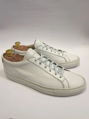 Common Projects Achilles Low 41 - Ikoniska lyxsneakers. Spås bli nästa stora grej hos Grischkillarna. Passar en 42. Skoblock medföljer inte. Nypris runt 4000kr