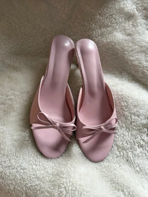 Rosa klackar  - Säljer ett par ljusrosa klackar med öppen tå och söt rosettdetalj framtill. OBS: ganska ostabila och svåra att gå i💕