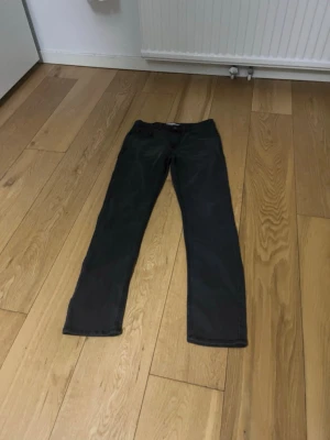 Svarta slim fit jeans från Lee - Snygga svarta slim fit jeans från Lee med klassisk femficksdesign och knappgylf. Jeansen har en smal passform och är tillverkade i ett mjukt denimtyg med lite stretch för extra komfort. Perfekta till en avslappnad streetwear-look.