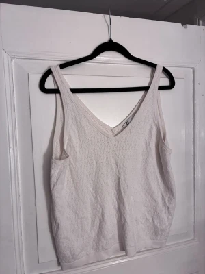 Vit stickad linnetopp med v-ringning Cubus - Säljer en vit stickad linnetopp från Cubus med v-ringning och breda axelband. Toppen har ett diskret hålmönster och är perfekt för varma dagar. Enkel att matcha med både jeans och kjol. Passar L