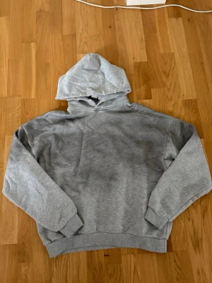Grå hoodie från Acne Studios - Säljer en grå hoodie från Acne Studios med tryck på ryggen där det står 'Acne Studios STOCKHOLM 1996'. Hoodien har huva, ribbade muddar och är gjord i mjukt sweatshirtmaterial. Perfekt för en chill och stilren look.