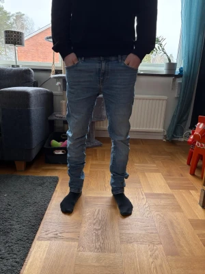 Ljusblå Slimfit Jeans - Snygga och bekväma jeans i klassisk mellanblå tvätt. Slim/regular passform som sitter fint över benen utan att vara för tight – ger en stilren och modern look som funkar både till hoodie, sweatshirt eller skjorta.  Mjuk och följsam denim med skön stretchkänsla, perfekta för vardag och skola/jobb. Klassisk 5-ficksmodell med dragkedjegylf.  I bra skick, väl omhändertagna och fortfarande fräscha i både färg och form.  Ett par tidlösa basjeans som passar till allt! 👖✨