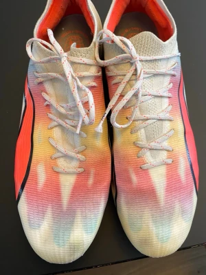 Nike färgglada Mercurial fotbollsskor - Säljer ett par Nike Mercurial fotbollsskor med grymt färgglad design i vitt, rött, orange och blått. Skorna har snörning, låg profil och ovandel i syntetmaterial för lätt känsla och bra bollkontroll. Perfekta för dig som vill sticka ut på planen!