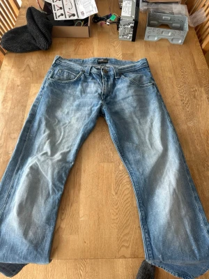 Blå jeans från Lee med raka ben - Snygga blå jeans från Lee med klassisk femficksdesign och raka ben. Jeansen har en ljus tvätt med slitningar och Lee-logga på bakfickan. Tillverkade i bomull för en bekväm känsla och avslappnad look.