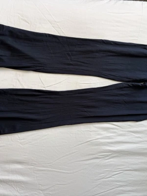 Mörkblåa yogapants - Ett par mörkblpa yogapants med smal passform och stretchigt material. Perfekta att matcha med oversized tröjor eller hoodies. Klassisk modell utan synliga detaljer eller fickor. Har en nedvikbar kant. Varan har små hål se bild 3,4,5 men inget större och jätte synligt. Köpare står för frakt. 