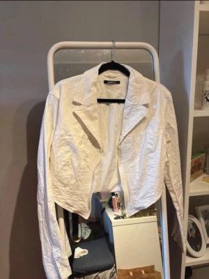 Vit croppad jacka från Gina Tricot - Snygg vit croppad jacka från Gina Tricot med dragkedja framtill och klassisk krage. Jackan har lång ärm och är tillverkad i ett lätt bomullsmaterial. Perfekt för att lyfta din outfit med en fräsch och trendig look.