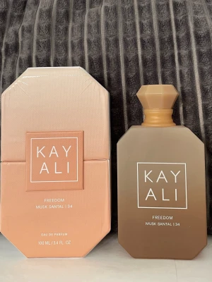 Kayali Freedom Musk Santal 34 - Kayali Freedom Musk Santal 34 eau de parfum 100ml flaska köpt från sephora  öppnad nu i juni 2026  Noter  Pink pepper Soft freesia  Soft Lily  Orange blossom Candied amber Musk santal   Den är endast test sprayad.  Se bilder på mängd kvar, flaska, automizern och.batchkod. . Påminner lite om valaya. Jätte fin doft. 