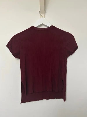 Vinröd ribbad topp - Vinröd ribbad topp. Något kortare framtill. Inköpt ifrån Plick och ursprungligen Bershka. Använt fåtalet gånger och i fint skick. Storlek XS. 