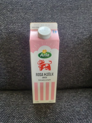 Arla Rosa Mjölk dryck jordgubb - En 1-liters förpackning Arla Rosa Kartongen är vit och rosa med ett lekfullt tryck av en rosa ko och jordgubbar. Skruvkork på toppen och tydliga rosa ränder på framsidan. Är tom.