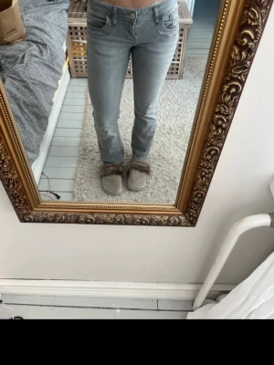 Ljusgråa bootcut jeans - Säljer ett par ljusgråa bootcut jeans med klassisk femficksdesign och låg midja. Jeansen har en enkel look utan slitningar och är perfekta för en avslappnad stil. Passar dig som gillar en tidlös och clean vibe.