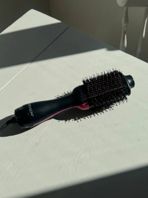 Revlon svart och rosa varmluftsborste - Säljer en svart och rosa varmluftsborste från Revlon. Borsten har ett ovalt borsthuvud med täta piggar och ett ergonomiskt handtag. Perfekt för att styla och torka håret samtidigt. Utrustad med sladd och EU-kontakt.