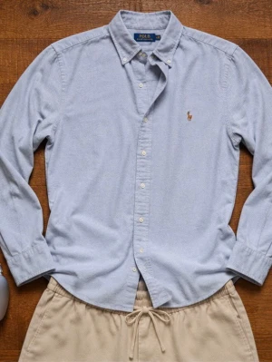 Ralph Lauren Skjorta Herr Small Grå/ Blå  - Klassisk Ralph Lauren Oxford-skjorta i en stilren ljusblå nyans. Perfekt till både vardag och mer uppklädda tillfällen. Ikonisk broderad logga på bröstet och button-down krage. Lätt att matcha med chinos, linnebyxor eller jeans. Kommer från ett rökfritt hem.                         Snabb leverans 📦                                        Bundledeals finns 