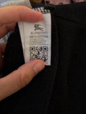 Limited hoodie med rutigt mönster - Snygg hoodie i 100% bomull. Svart bas med klassiskt rutigt mönster i grått, beige och rött samt ett broderat Burberry B på bröstet. Hoodien har huva och ribbade muddar vid ärmar och nederkant. Perfekt för dig som vill ha en stilren och trendig look.