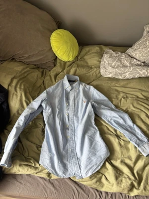 Ljusblå skjorta Polo Ralph Lauren - Ljusblå skjorta Polo Ralph Lauren, är som ny men den har bara andvänts en gång. Bredd 56cm, längd 68cm