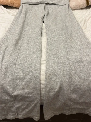 Grå mjukisbyxor från H&M - Säljer ett par ljusgrå mjukisbyxor från H&M med raka ben och bred resår i midjan. Tillverkade i en mjuk bomullsblandning med 54% bomull och 46% polyester. Perfekta för chill dagar eller när du vill vara extra bekväm.