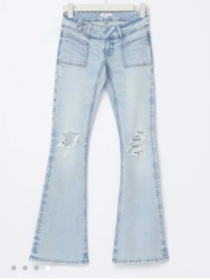 Ljusblå bootcut jeans med hål - Säljer ett par lågmidjade ljusblå bootcut jeans med slitna detaljer på båda benen och stora fickor fram. Säljer dem på grund av att dem ej går att lämna tillbaka för lapparna är av. Ångrat köp och aldrig använt så därför säljs dom. 