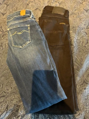 Två par slim  jeans från Nudie och replay  - Säljer två par slim jeans från Nudie, ett par i klassisk blå denim med ljusa sömmar och ett par i svart tvätt. Båda har femficksmodell och Nudie-logga på bakfickan. Perfekta för dig som gillar en smal passform och stilren look.