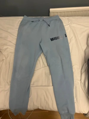 Ljusblå mjukisbyxor från Hoodrich - Säljer ett par ljusblå mjukisbyxor från Hoodrich med broderad logga på vänster lår. Två fickor vid sidan och 1 diskret vid innerlåret(se bild) Perfekta för chill dagar och streetwear vibes. Nypris cirka 700. Paketpris för både Hoodien och byxorna 650