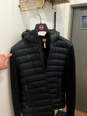 Svart pufferjacka med stickade ärmar - Snygg mörkblå cardigan från colmar. Väldigt bra skick och använd endast en höst säsong. Passar riktigt bra till det mesta och är varmare än vad man tror. Den har blivit lite förliten därför jag säljer! Skriv vid funderingar och frågor! Pris kan även diskuteras vid snabb affär.