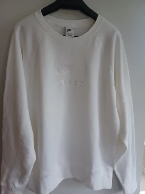 Ny sweatshirt från Nike Air - Säljer en ny, oanvänd stilren vit sweatshirt från Nike Air med diskret broderad logga och text på bröstet. Tröjan har rund halsringning och är tillverkad i mjukt bomullsmaterial. Perfekt för en clean och sportig look.