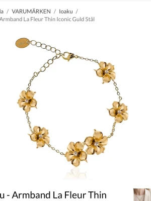 Guldfärgat armband med blommor Loaku - Snyggt armband i guldfärgat stål från Loaku med tunna länkar och fem detaljerade blommor. Varje blomma har en liten glittrande sten i mitten som ger extra lyxig känsla, en sten saknas! Perfekt för dig som gillar eleganta och trendiga accessoarer.🌸