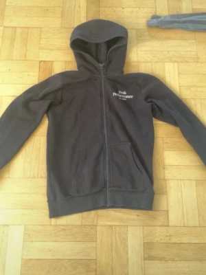 Svart hoodie från Peak Performance - Säljer en svart hoodie från Peak Performance med dragkedja framtill och två fickor. Klassisk logga broderad på bröstet. Hoodien har en skön huva och ribbade muddar vid ärmslut och nederkant. Perfekt för chill dagar eller till träningen.