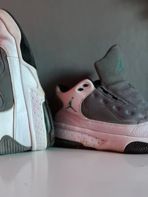 Jordans Max aura 2 neptune green  - Snygga sneakers från Jordan i vitt och grått med gröna detaljer. Skorna har en låg siluett, meshpaneler på sidan och klassisk Jumpman-logga i grönt. Ovandelen är i läder och mesh, sulan är vit med svarta detaljer undertill. Perfekta för dig som gillar streetwear.
