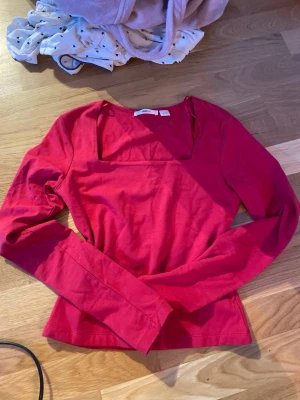 Röd långärmad topp från Gina Tricot - Snygg röd långärmad topp från Gina Tricot med fyrkantig ringning. Perfekt att styla med jeans eller kjol. Tillverkad i mjuk bomull som känns skön mot huden.