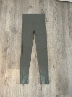 Grågröna höga tights - Snygga grågröna leggings med hög midja och tight passform. Tillverkade i ett stretchigt material som passar perfekt för träning eller chill. Inga synliga loggor eller detaljer, enkel och clean design.