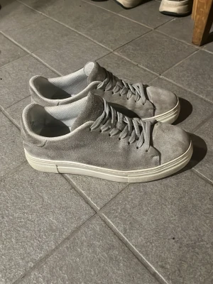 Grå selected homme mockasneakers med vit sula - Stilrena sneakers i grå mocka med matchande grå skosnören och tjock vit sula. Klassisk låg modell som passar till det mesta. Insidan är fodrad i textil för extra komfort. Perfekta för dig som gillar en clean och enkel look.