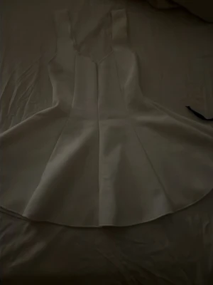 Vit kort tröja från Zara - Säljer en vit kort tröja från Zara med breda axelband och markerad midja. Tröjan har en utsvängd kjol och är tillverkad i ett mjukt material som känns bekvämt mot huden. Perfekt för dig som gillar stilrena och enkla plagg.