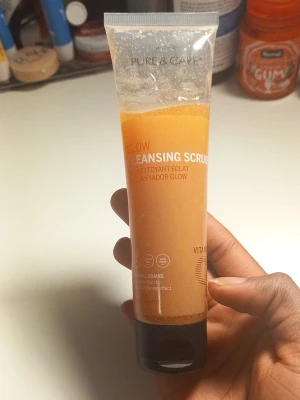 Glow Cleansing Scrub med vitamin C från Pure & Care - Glow Cleansing Scrub i orange tub med svart lock. Innehåller naturliga korn och vitamin C för en fräsch och strålande hud. Tuben är genomskinlig så man ser den orangefärgade skrubben inuti. Perfekt för dig som vill ha glow och mjukare hud.