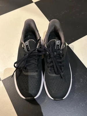 Footjoy golfskor - Svarta sneakers från FZ Forza med ventilerande mesh-ovandel och vita detaljer på sulan. Skorna har klassisk snörning, låg profil och slitstark yttersula i gummi med svart och vit design. Perfekta för en sportig look.