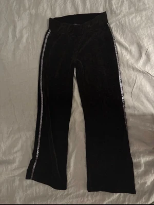 Mörkblåa mjukisbyxor från Ricarda M - Säljer ett par mörkblåa mjukisbyxor från Ricardo M. Byxorna har raka ben och en silvrig detalj längs sidorna som ger en snygg kontrast. Perfekta för en chill och trendig look.