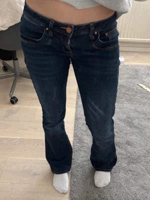 Ltb jeans  - Säljer ett par mörkblå bootcut jeans med klassiska fem fickor och kontrastsömmar. Jeansen har en låg midja och stängs med knapp och dragkedja. Materialet är denim och passformen är något utsvängd nedtill.
