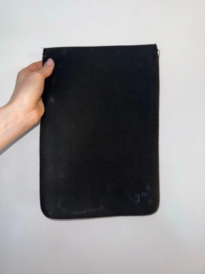 Svart laptopfodral 13 tum - En stilren svart datorväska i mjukt material, perfekt för en 13-tums laptop. Fodralet är enkelt och smidigt utan extra fack, med diskret design, ingen dragkedja upptill. Passar dig som vill ha ett minimalistiskt skydd till din dator.