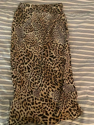 Leopardmönstrad långkjol från Zara - Säljer en snygg långkjol från Zara med leopardmönster i beige, brunt och svart. Kjolen har en rak passform och är tillverkad i ett mjukt, lätt material som ger ett coolt intryck. Perfekt för dig som vill sticka ut med ett djurmönster.