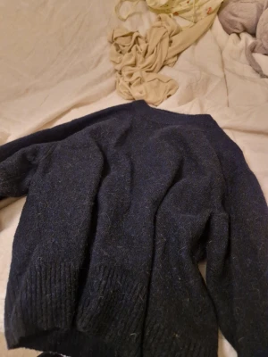 Mörkblå stickad tröja från Gant - Mysig mörkblå stickad tröja från gina tricot med klassisk rund halsringning och breda ribbade muddar vid ärmslut och nederkant. Perfekt för lager på lager och enkel att matcha med jeans eller kjol. Materialet känns mjukt och värmande.