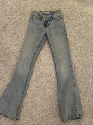 Ljusblå bootcut jeans Perfect Jeans - Säljer ett par ljusblå bootcut jeans från Perfect Jeans. Jeansen har klassisk femficksmodell, normal midja och utsvängda ben. Tillverkade i denim med snygg tvätt och detaljerade sömmar. Perfekta för en avslappnad och trendig stil.