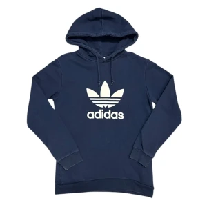 Adidas Trefoil Zip Pocket Navy Hoodie - Den här varan kommer auktioneras ut på Sneakershyllan x Plick Live den Torsdagen 16 juli kl 19. Marinblå hoodie från Adidas med Trefoil och dragkedjeficka på sidorna, storlek Small och gott skick