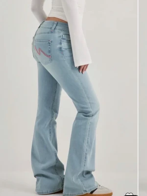 Ljusblå bootcut jeans (I accept bud!!) - Snygga low waisted ljusblå jeans med bootcut passform och klassisk femficksdesign😍. Jeansen har broderade detaljer i rosa på bakfickorna och är tillverkade i denim. Perfekta för en avslappnad och trendig look.💕