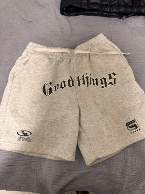 Grå sweatshorts med tryck - Snygga grå sweatshorts med texten 'Good things' i svart på framsidan. Shortsen har resårmidja med snörning och två sidofickor. Perfekta för en avslappnad stil och har tryckdetaljer från Growth och femstjärnig logga.