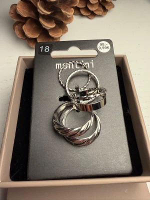 Snygga silvriga ringar från Montini - Flera silvriga ringar i olika designer från Montini. Setet innehåller både släta och tvistade ringar i metall, perfekta att mixa och matcha. Alla ringar har en modern och trendig look som passar till många stilar.