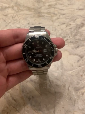 Rolx Role Submariner  - Säljer en klassisk Submariner med svart urtavla och silverfärgad länk i rostfritt stål.
