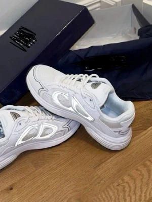 Vita sneakers med silvriga detaljer - Snygga vita sneakers med silvriga detaljer och meshpaneler på sidorna. Skorna har en chunky sula och klassisk snörning. Perfekta för dig som gillar en sportig och modern look. Materialet är en mix av textil och syntet.